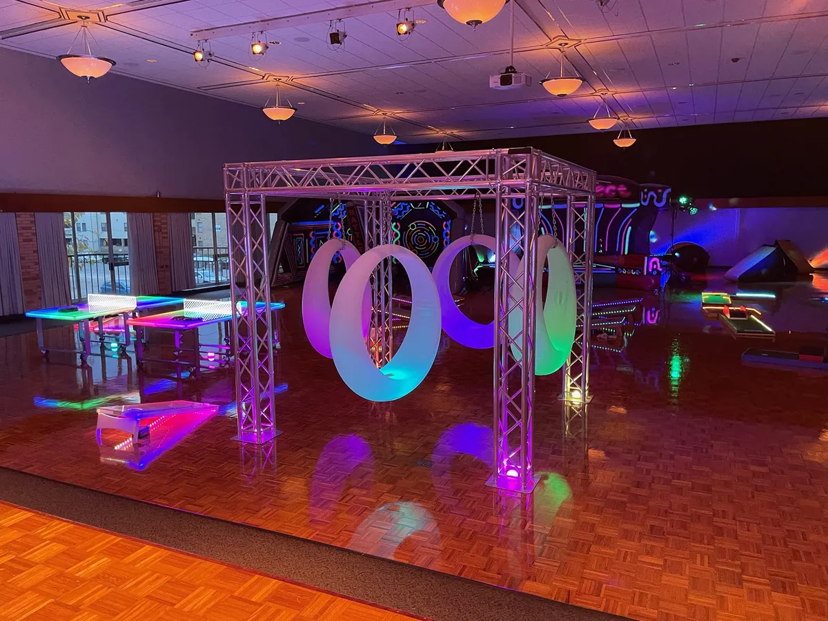 Four glowing LED swings suspended from up-lit trussing, set up for an evening event in Chicago.