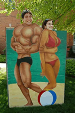 On The Beach photo stand rental with muscle man and bikini woman face-in-the-hole cutouts for event photos